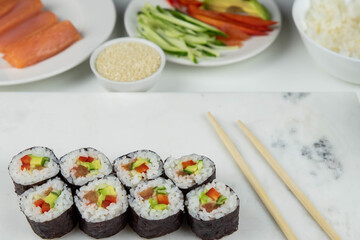 Sushi rolls prepared by professional asian chef with traditional Japanese ingredients. Salmon, rice, vegetables, sesame seeds.  Sushi cooking and making concept