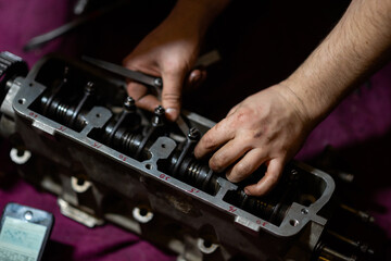 Fototapeta na wymiar blurred image, male hands adjusting valve clearances on the cylinder head. cylinder head repair