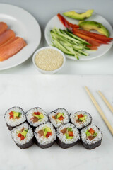 Sushi rolls prepared by professional asian chef with traditional Japanese ingredients. Salmon, rice, vegetables, sesame seeds.  Sushi cooking and making concept