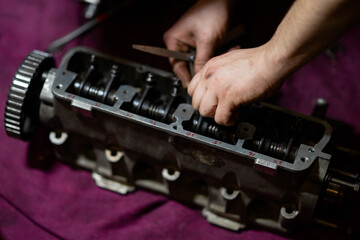 Fototapeta na wymiar blurred image, male hands adjusting valve clearances on the cylinder head. cylinder head repair