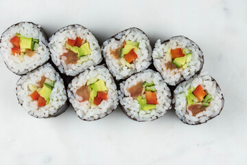Sushi rolls prepared by professional asian chef with traditional Japanese ingredients. Salmon, rice, vegetables, sesame seeds. 