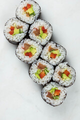 Sushi rolls prepared by professional asian chef with traditional Japanese ingredients. Salmon, rice, vegetables, sesame seeds. 