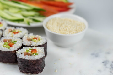 Sushi rolls prepared by professional asian chef with traditional Japanese ingredients. Salmon, rice, vegetables, sesame seeds. Sushi cooking and making concept