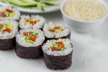 Sushi rolls prepared by professional asian chef with traditional Japanese ingredients. Salmon, rice, vegetables, sesame seeds. 