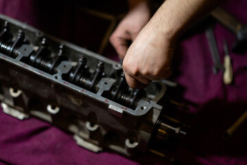 Obraz na płótnie Canvas blurred image, male hands adjusting valve clearances on the cylinder head. cylinder head repair