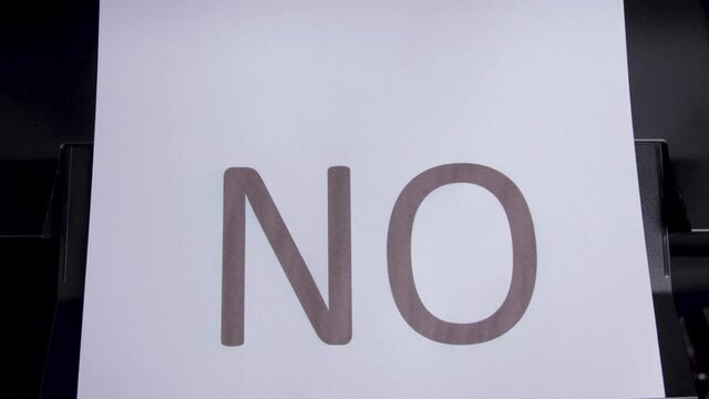 The printer print the word NO on a white sheet. Top view. Close up