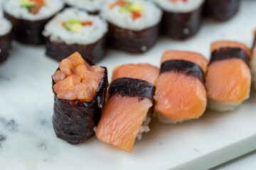 Sushi rolls prepared by professional asian chef with traditional Japanese ingredients. Salmon, rice, vegetables, sesame seeds. 