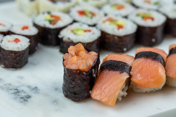 Sushi rolls prepared by professional asian chef with traditional Japanese ingredients. Salmon, rice, vegetables, sesame seeds. 