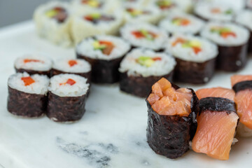 Sushi rolls prepared by professional asian chef with traditional Japanese ingredients. Salmon, rice, vegetables, sesame seeds. 