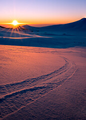 Fototapeta na wymiar tramonto sulla piana di campocatino innevato. vista sugli impianti sciistici, tracce nella neve