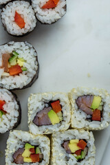 Sushi rolls prepared by professional asian chef with traditional Japanese ingredients. Salmon, rice, vegetables, sesame seeds. 