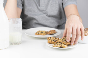 Man having breakfast with milk or kefir and healthy grain cookies on white background. Young man eating healthy food. 