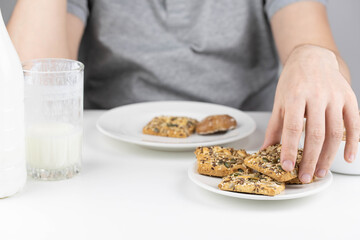 Man having breakfast with milk or kefir and healthy grain cookies on white background. Young man eating healthy food. 