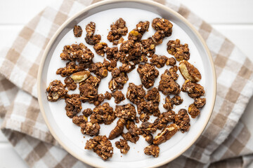 Chocolate breakfast cereal. Morning granola with milk in bowl.