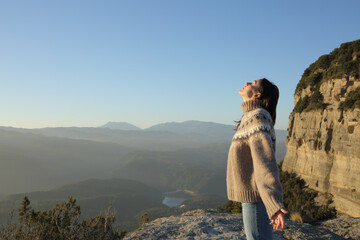 Woman in sweater breathing fresh air in the mountain in winter