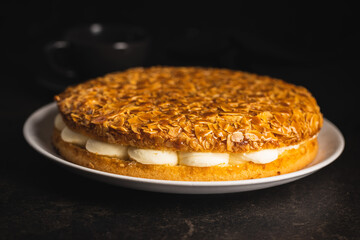  Sweet almond cake. Pie with cream and almonds on black table.