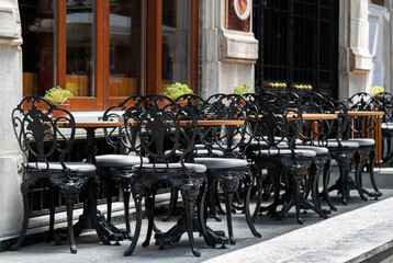 Street outdoor view of old fashion cozy cafe terrace with empty black wrought iron chairs and tables in summer morning in Istanbul. Restaurant tables waiting for customers at an outdoor terrace
