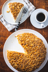 Sliced sweet almond cake on plate. Pie with cream and almonds.