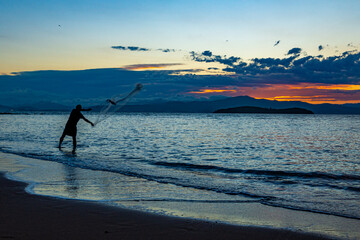 Our daily fish. Silhouette of a fisherman throwing the fishing net, called 