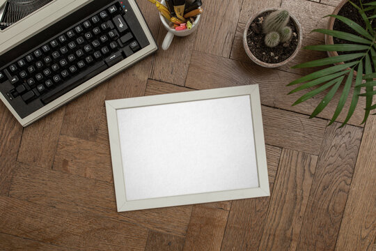 A portrait picture frame mockup. Wall art gallery. Vintage typewriter on old wooden bench, table. White wall background. Little pots and plants. Scandinavian interior, neutral color palette.