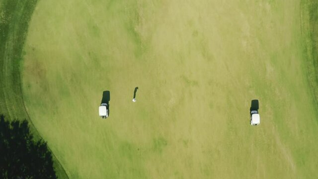 Albufeira, Portugal. White golf cars on the field covered with lush green lawn. Aerial footage of golf players during a competition. High quality 4k footage