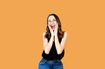 Surprised happy woman looking sideways in excitement. Isolated on orange background