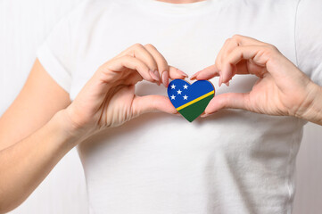 Flag of the Solomon Islands in the shape of a heart in the hands of a girl. Love Solomon Islands. The concept of patriotism and tourism
