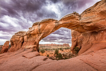 The famous Broken Arch in the Arches National Park, Utah and dramatic dark clouds