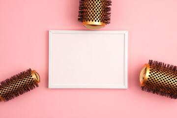 Plastic frame flat lay of set of professional gold round hair brushes for styling at the right of the image template with copy space on pink. Hairdresser salon equipment concept, premium set