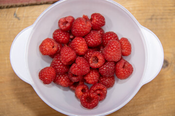A bowl of delicious red raspberries in a white bowl