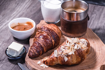 Croissants, milk and coffee on a wooden table in a low key. The concept of traditional breakfasts and delicious food