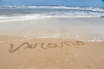 handwritten poster on sand indicating summer on the beach