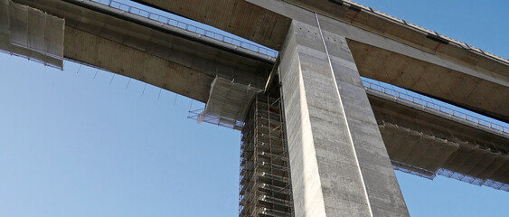 The reinforced concrete columns of a highway viaduct with scaffolding and protective nets