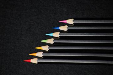 Sharpened wooden color pencils with black body color on the black felt solid fond background...