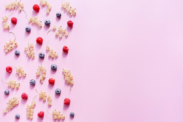 Colorful pattern of blueberries, currant berries white, raspberries on pastel pink background. Flat lay, top view, copy space.