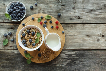 Breakfast with muesli, fresh berries blueberries on wood background. Healthy food concept. Flat lay, top view, copy space