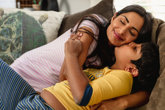 Smiling Indian mom embracing son at home