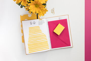 Opened to-do notebook with a pink envelope over one page and some yellow highlighted lines on the...