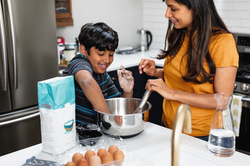 Indian mother and son baking in kitchen, having fun