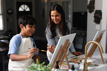 Indian mother and son laughing, painting at home, do-it-yourself