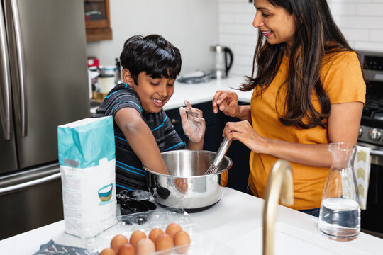 Indian Mother And Son Baking In Kitchen, Having Fun