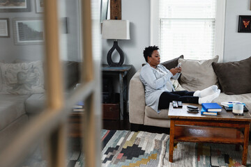 Woman sits on couch while sending messages on phone