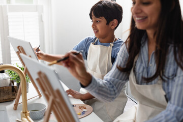 Indian mother and son laughing, painting at home, do-it-yourself