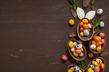 Easter eggs hunt concept background with chocolate eggs and bunny on wooden table copy space. View...