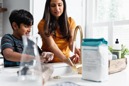 Indian mom and son washing hands in kitchen