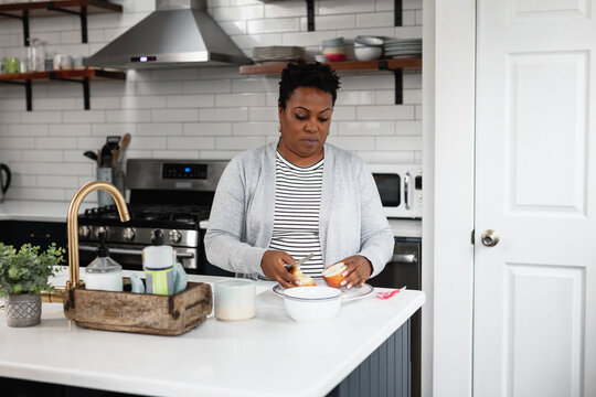 Black woman prepares a lite snack in the kitchen
