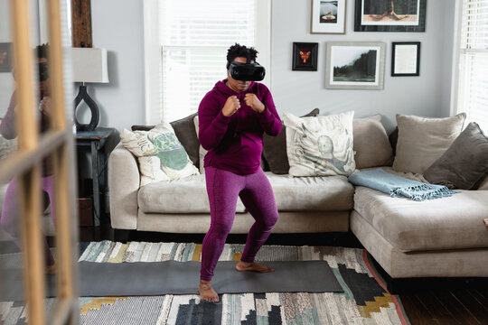 African American woman doing virtual reality VR boxing at home in living room