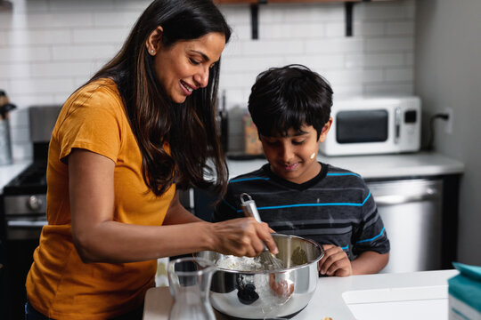Indian woman and son bakes homemade cookies at home in kitchen