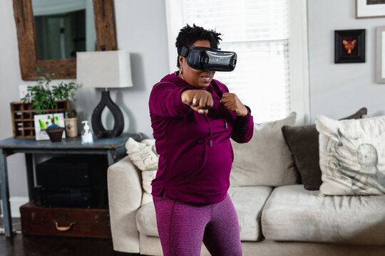 African American woman doing virtual reality VR boxing at home in living room