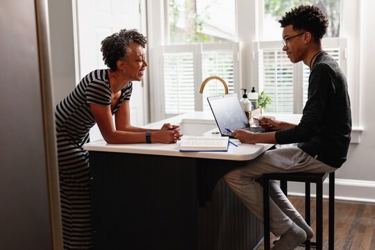 Black Mother Talking With Son In Kitchen At Home